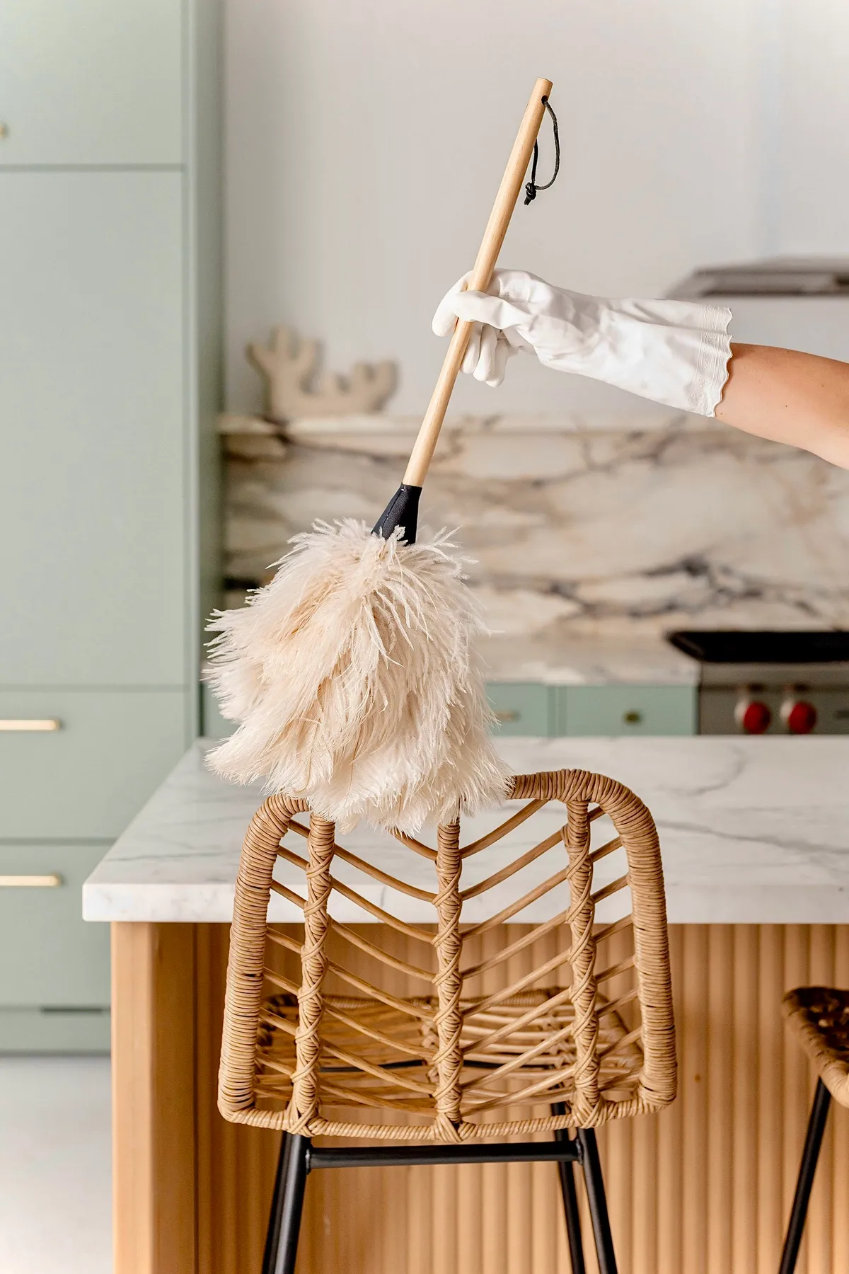 Feather dusting a woven chair in a cottage kitchen