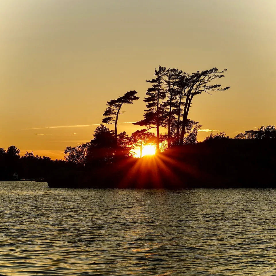 Silhouetted island with pine trees at sunset over the lake